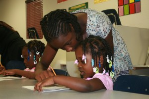 At Bible Truth school, Lizzie Bilogo-Nguema, 12, helps 3-year-old Delilah Prevot with math. The school features a lot of interaction between students of different ages.